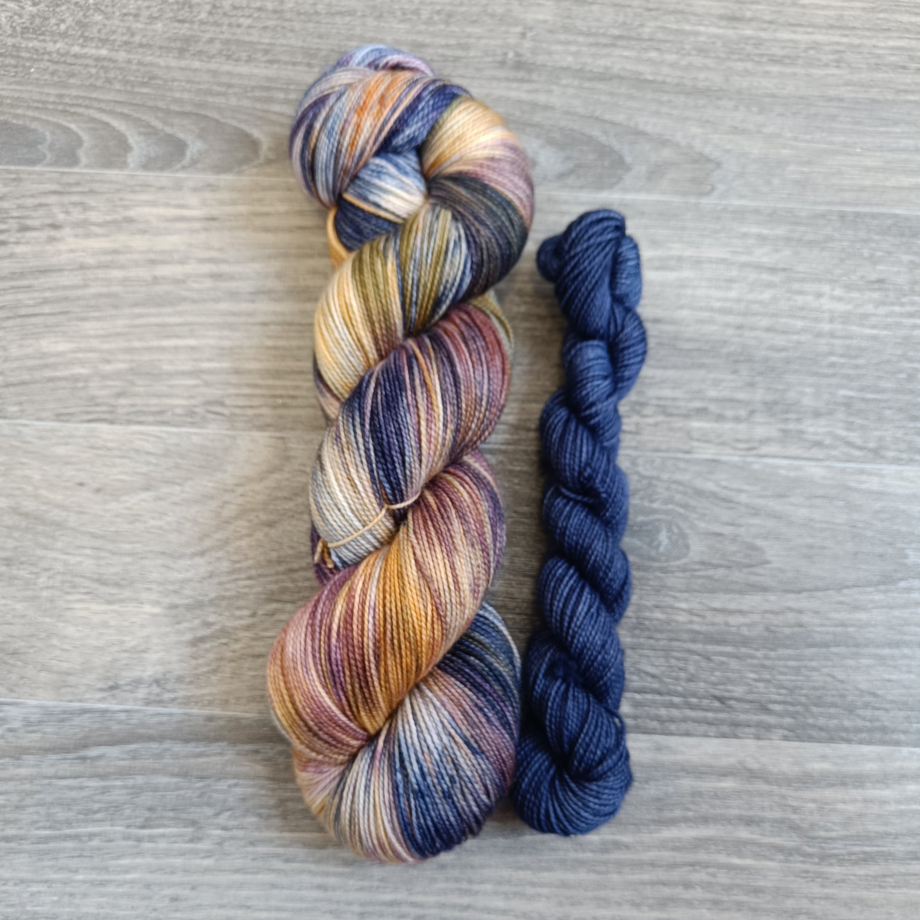 Skein of yarn in colourway Mystical Dreams with a co-ordinating  blue mini skein